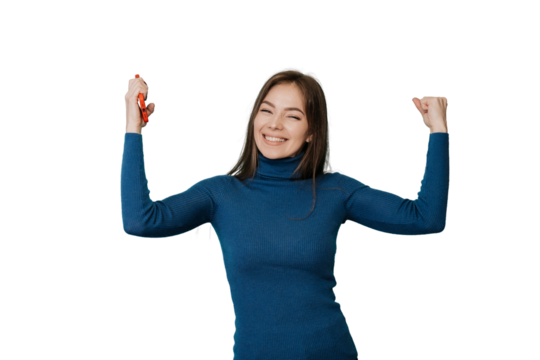 Celebrating young attractive girl raises her hands up smiling holding phone, happy received good news, standing over transparent background. Happy Italian young woman clenched her hands like a winner.