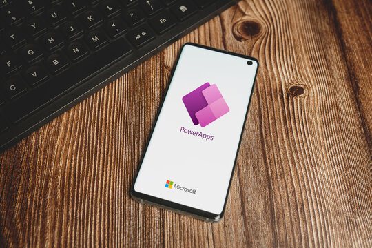 Microsoft Power Apps logo and black keyboard on wooden background. Swansea, UK - October 24, 2022.