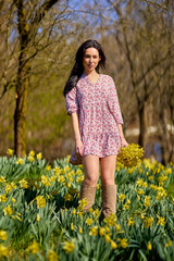 A  beautiful woman in a garden with yellow snowdrops on a spring day.