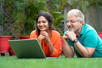 Indian senior man and his daughter using laptop at garden.