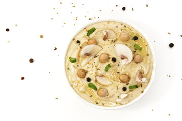 Hummus with mushrooms on a white background. Hummus in a plate topped with chickpeas, sesame seeds, onion, oil and spices. Culinary and food menu photo