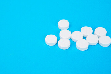 Heap of round white pills on blue background