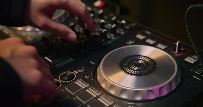 HD of an East Asian dj playing his flashing modern console mixer turntable