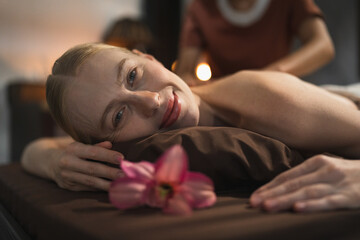 Obraz na płótnie Canvas Beautiful caucasian woman having shoulder massage at night spa salon