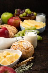Jewish Shavuot Holiday Card. Dairy Products, Fruits, Cheese, Bread, Milk on Brown Wooden Background.