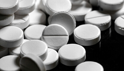 Close up of white painkiller tablet on a reflective black backgr