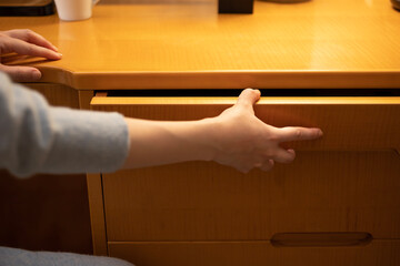 机の引き出しを開ける女性の手