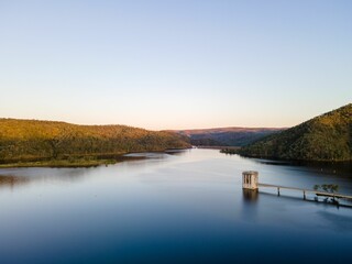 Mesmerizing view of calm lake water surrounded by green mountains and trees against a clear sky