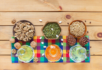 Three types of healthy organic vegetable oil - from pumpkin seeds, from pine nuts and from walnuts on checkered napkin on wooden table. Vegetable oils containing polyunsaturated acids omega-3, omega-6