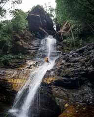 Few adventurers abseiling a waterfall cliff