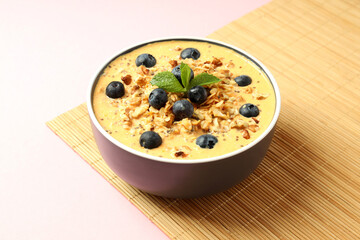 Smoothie with different ingredients on bamboo mat on pink background