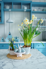 Blue kitchen interior with furniture. Stylish cuisine with flowers in vase. Wooden kitchen in spring decor. Cozy home decor. Kitchen utensils, dishes and plate on table. kitchen island in dining room,