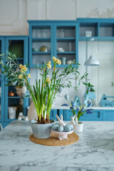 Blue kitchen interior with furniture. Stylish cuisine with flowers in vase. Wooden kitchen in spring decor. Cozy home decor. Kitchen utensils, dishes and plate on table. kitchen island in dining room,