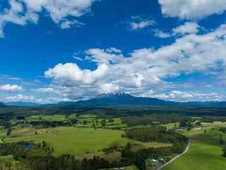 Fototapeta premium Drone shot of the Calbuco Volcano under the blue cloudy sky in Chile with fields on its foot