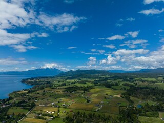 Fototapeta na wymiar Drone shot of the Osorno Volcano under the blue cloudy sky in Chile with Llanquihue lake on its foot