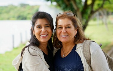 Obraz premium Hispanic and Caucasian mother with daughter smiling to the camera on blur background