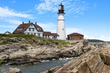 Fototapeta na wymiar Portland lighthouse with a house by the sea at Fort Williams Park