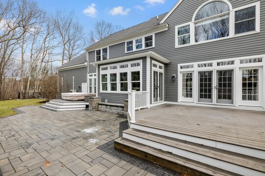 Low Angle View Of A Private House With A Gray Exterior And A Garden Out Front On A Sunny Day