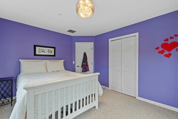 a bright purple bedroom with an antique bed and a white foot stool