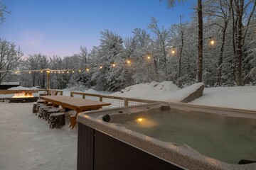 a hot tub sitting under an umbrella in the snow covered trees