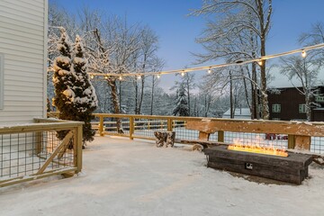 a snowy deck has a firepit and trees with snow on the ground