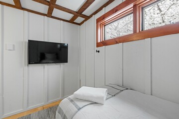 Comfortable white bedroom with a widescreen TV hanging on the wall