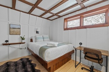 Comfortable white bedroom with a desk, chair, and extensive bed