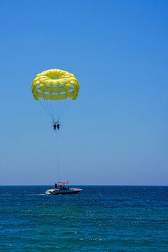Parasailing on a yellow parachute against the blue sky. Beach extreme adventures. Background vacation, photo for postcards, tourist and travel guide. The concept of summer holidays, vacation, tourism