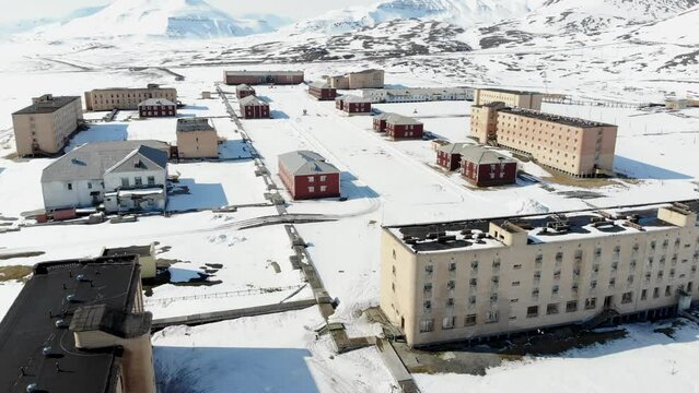 Drone shot of the snow covering the houses, road and mountains of Pyramiden town in Spitsbergen