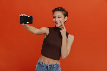 Young beautiful short-haired smiling woman taking selfie with phone