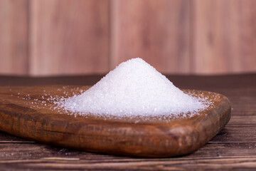 Granulated sugar. White refined sugar on wood background.