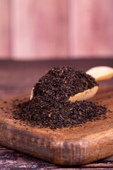 Turkish black tea. Black tea in spoon on wood background. Close up
