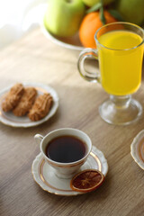 Cup of tea, plates with cookies, glass of orange juice, books, reading glasses, bowl of fruit and candles on the table. Selective focus.