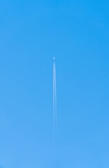 Obraz premium Vertical shot of a plane trail with sky in the background