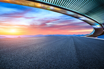 Asphalt road and bridge with mountain background at sunrise