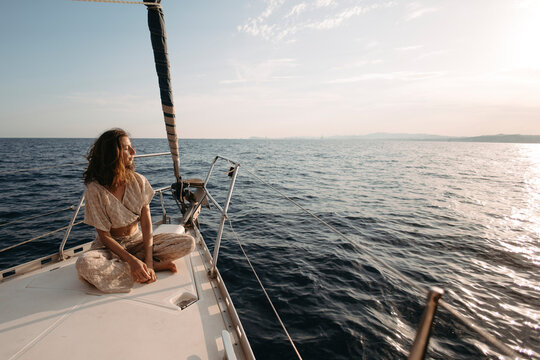 Woman sitting on sailboat at sunset