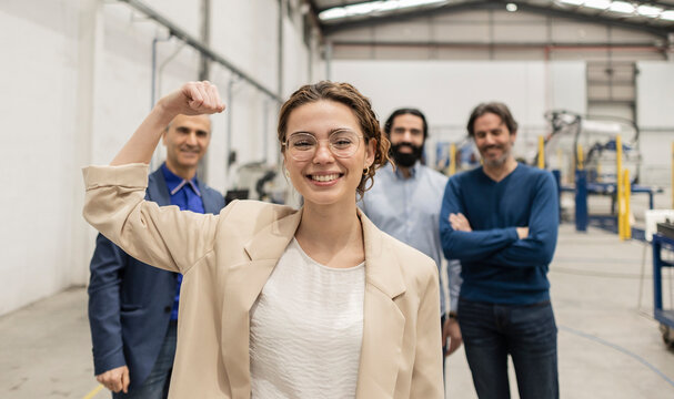 Happy businesswoman flexing muscles standing in front of colleagues