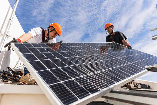 Engineers holding solar panel on roof