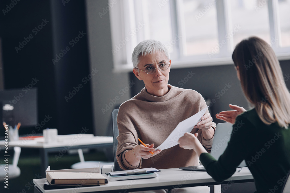 Wall mural Confident female HR manager having interview with job candidate while sitting at the office desk