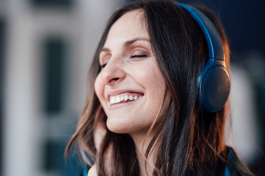 Happy woman wearing wireless headphones listening to music