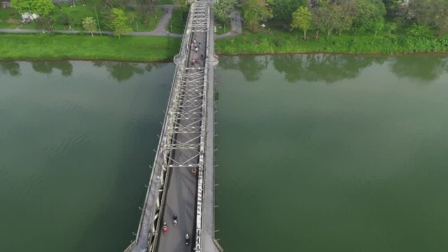 Aerial drone footage above the Than Tien bridge built by Eiffel industry in Hu&eacute;, Vietnam. Camera moves foward above the bridge and the traffic (moto and cyclo only) 
