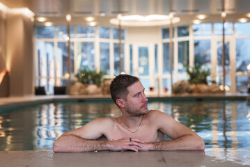 Young man swimming in a swimming pool in a luxury hotel. Enjoying beautiful leisure near the SPA.
