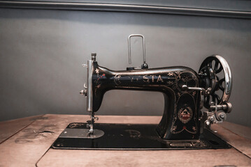 Closeup of black vintage sewing machine in front of gray wall in room of hotel