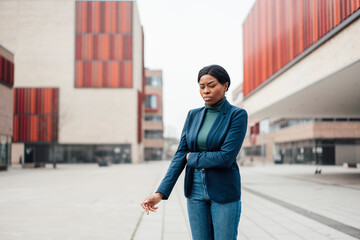 Businesswoman with cigarette standing on footpath