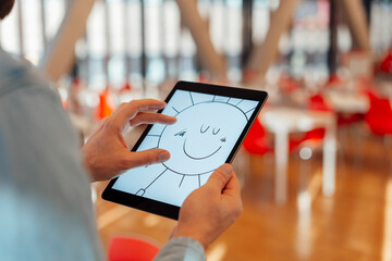 Businessman zooming design of sun on tablet PC in office