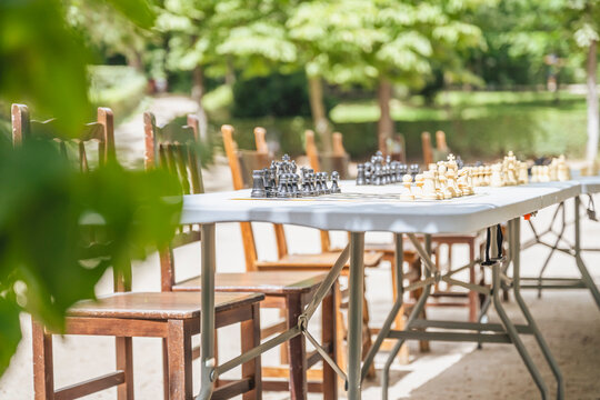 Spain, Madrid, Empty chairs in front of outdoor chess tables in El Retiro Park