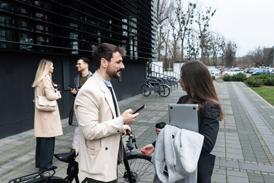 A regular day for working people standing talking walking in front of the office building where they work going to and from workplace. Businesspeople between staff meetings outdoor.