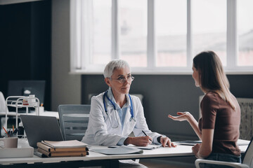Confident female doctor listening to the patient while sitting at the medical office