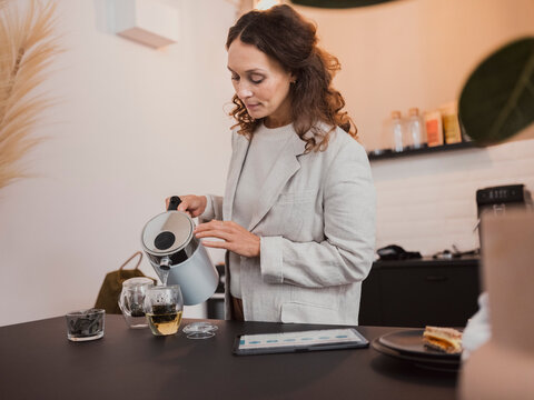 Woman making tea in kitchen at home