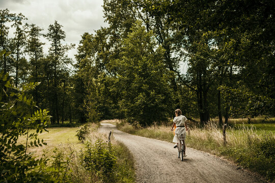 Woman riding bicycle on narrow dirt road